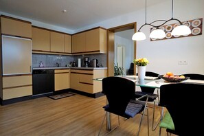 A modern kitchen with wooden cabinets, a dining table with chairs, and a coffee machine. - Apartment 'Festungsblick' with Terrace, Garage and Private Entrance (Koblenz)