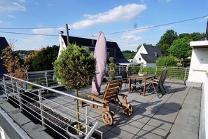 A terrace with a table and chairs, a small tree, and a railing. - Apartment 'Festungsblick' with Terrace, Garage and Private Entrance (Koblenz)