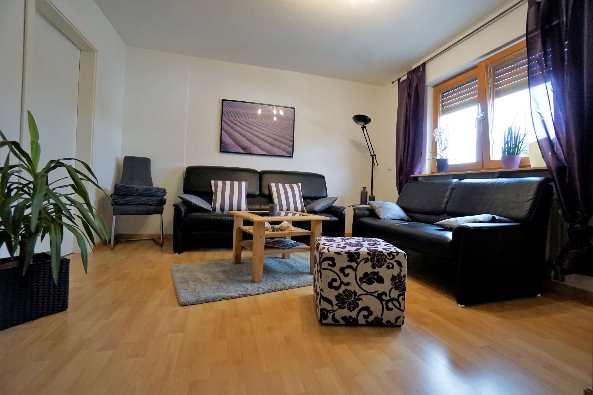 Ein Wohnzimmer mit einer Couch, einem Couchtisch, einem Teppich und einer Topfpflanze.