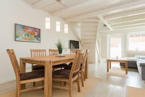 Ein Essbereich mit Holztisch und -stühlen, einem Bild an der Wand und einer Treppe, die in einen anderen Raum führt.