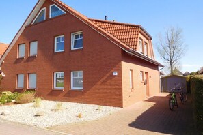 Ein zweistöckiges Backsteinhhaus mit geneigtem Dach und einer Garage, vor der ein Fahrrad abgestellt ist.