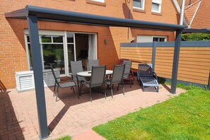 Un espace extérieur aménagé avec une table et des chaises, un banc et une clôture en bois.