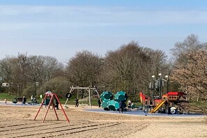 Ein Spielplatz mit Schaukeln, einer Rutsche und einer Kletterkonstruktion.