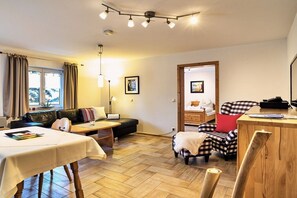 A cozy living area with a sofa, a dining table, a lamp, and a chair. - 4 Country House Farmer (Bodenmais)