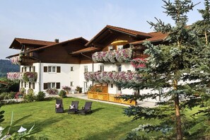 A two-story building with balconies, a well-maintained lawn, and outdoor seating. - 4 Country House Farmer (Bodenmais)