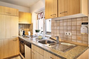 A kitchen with wooden cabinets, a stainless steel sink, and a built-in oven. - 4 Country House Farmer (Bodenmais)