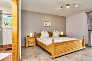 A bedroom with a wooden bed, bedside tables, a nightstand, a ceiling light fixture, and a window with curtains. - 3 Country House Farmer (Bodenmais)