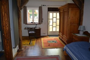Una habitació amb llit, escriptori i cadira, armari i porta que dona a l'exterior.