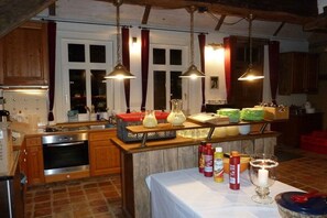 Una cocina con armarios de madera, horno de acero inoxidable, luces colgantes y una isla central con diversos utensilios de cocina.