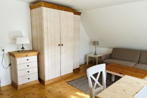 Une pièce comprenant une armoire en bois, une petite table avec une chaise, un canapé et une lampe.