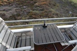 Ein Balkon mit Tisch und zwei Stühlen, mit Blick auf eine natürliche Landschaft.