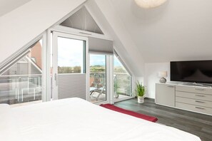 Une chambre moderne avec un grand lit, une télévision et un balcon doté de portes vitrées.