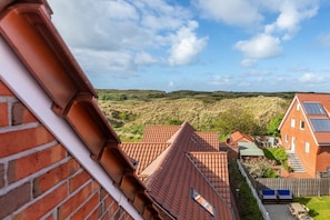 A residential area with houses featuring red-tiled roofs, a brick wall, and a view of the landscape. - Apartment in Juist with Wi-Fi and water park (Juist)
