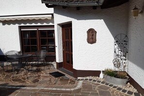 Ein Patio mit Steinböden, einer Holztür und einer weißen Wand mit einer verzierten Platte.