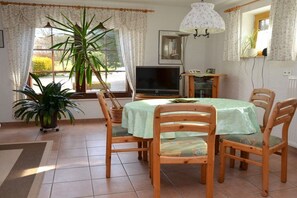 A dining area with a table and chairs, a television, and a potted plant. - Holiday apartment with 1 bedroom (Walsdorf-Zilsdorf)