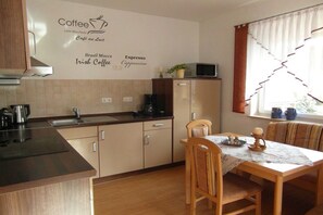 Eine Küche mit einer Wand zum Thema Kaffee, einem Esstisch mit Stühlen und einem Fenster mit Vorhängen.