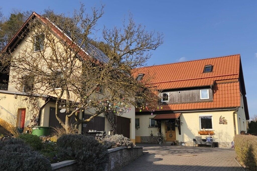 A two-story building with a red roof, a visible chimney, and a small window.