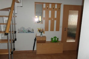 Una habitació amb una porta de fusta, un mirall, un taulell de fusta i una mitja de peu recolzada contra la paret.