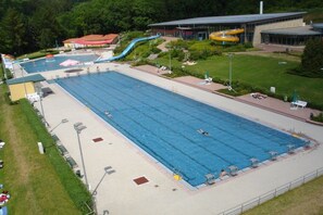 Ein großer Pool mit einer Rutsche und einem Gebäude mit Glasfenstern im Hintergrund.