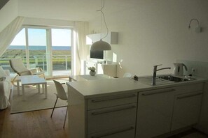 A modern kitchen with a large island, a dining area with a view, and a casual seating arrangement. - Holiday apartment with 1 bedroom (Cuxhaven)