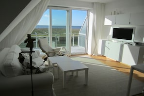 A modern room with a balcony, a television, and a sofa. - Holiday apartment with 1 bedroom (Cuxhaven)