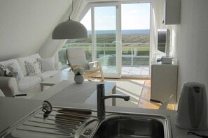 A modern kitchen with a large window, a dining area with a table and chairs, and a view of the countryside. - Holiday apartment with 1 bedroom (Cuxhaven)