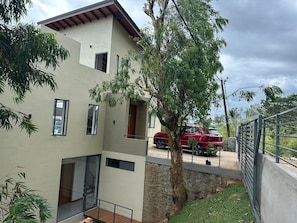 Une maison moderne à deux étages, avec une voiture rouge garée devant.