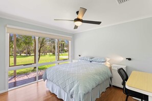 A bedroom with a bed, a desk, a chair, a ceiling fan, and large windows. - Isle Grove - Close to Cowes Beach (Cowes)