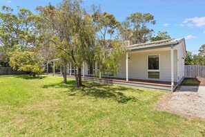 A single-story house with a covered porch, a fenced yard, and a tree in the foreground. - Isle Grove - Close to Cowes Beach (Cowes)