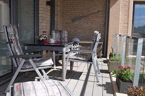 A balcony with a table and chairs, a potted plant, and a window. - Holiday apartment with 2 bedrooms (Varel-Dangast)