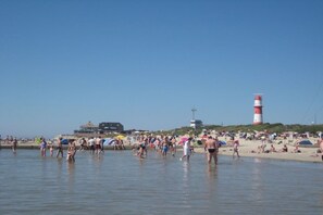 A beach with people, a lighthouse, and a building in the background. - Holiday apartment with 1 bedroom (Borkum)