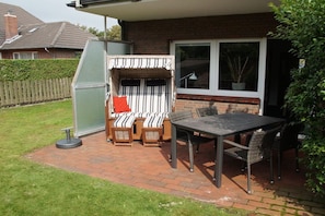 A patio with a table and chairs, a covered seating area, and a window. - Holiday apartment with 1 bedroom (Borkum)