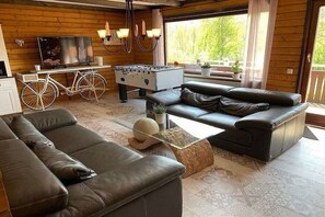 A modern living room with a sofa, coffee table, and a foosball table. - by the lake with views of the lake and the Bavarian Forest (Arrach\/ Kummersdorf)