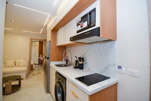 Een compacte keuken met een inbouwmagnetron, een spoelbak en een vaatwasser.