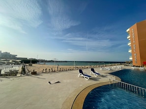 Ein Poolbereich mit Liegestühlen, freier Blick auf den Strand und ein Hotelgebäude mit der Aufschrift 'STORIA DEL MARE'.