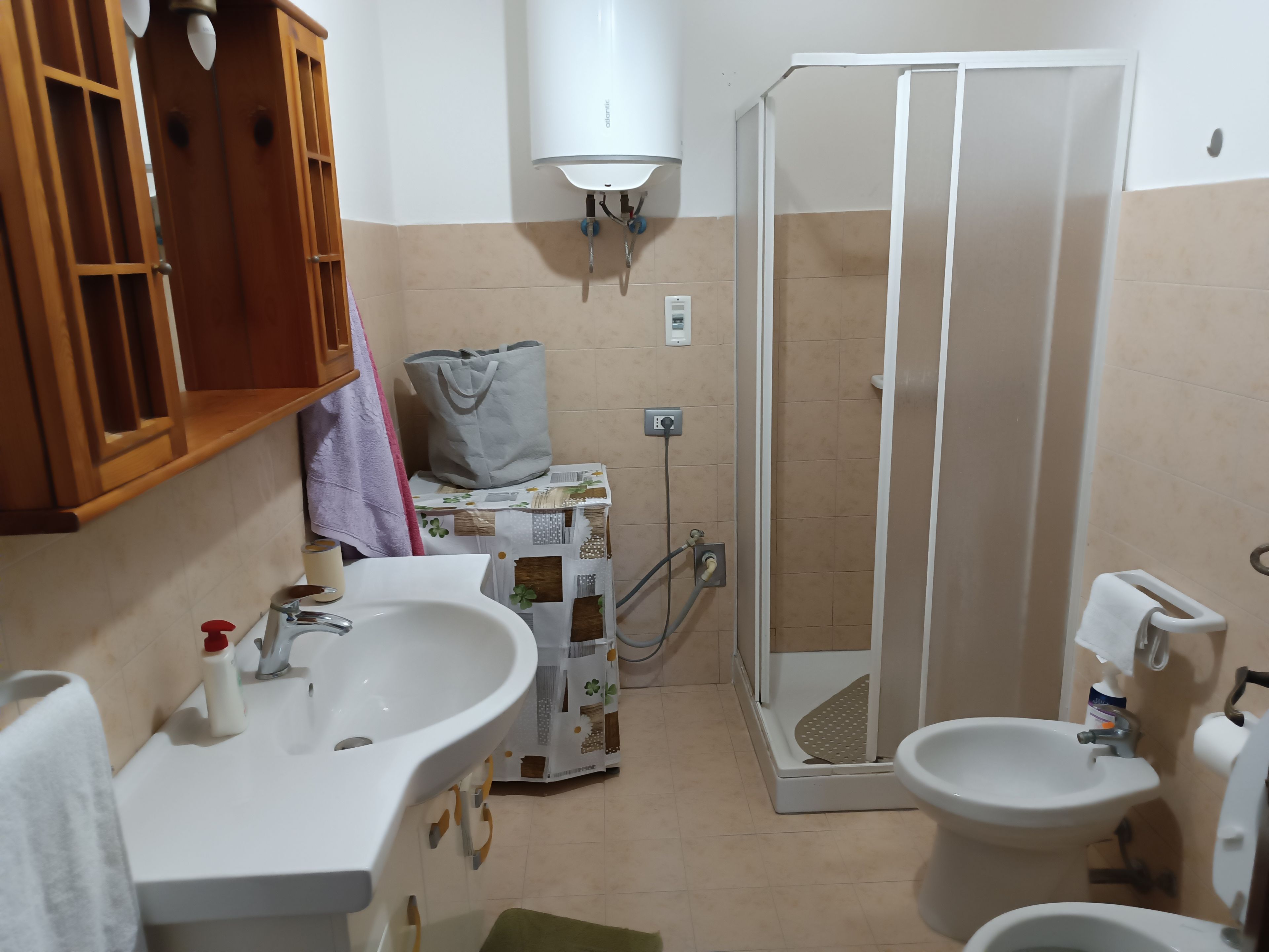 A bathroom with a sink, toilet, bidet, and a walk-in shower.