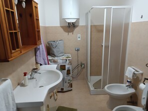 Ein Badezimmer mit Waschbecken, Toilette, Bidet und einer begehbaren Dusche.
