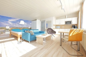 A modern interior with a bed, sofa, dining table, and chairs. - Holiday apartment with 1 bedroom (Norderney)
