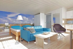 Een moderne kamer met een bed, een blauwe bank, een gestreept fauteuil en een tafel.
