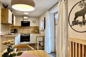 Eine moderne Küche mit Holzausstattung, einem Herd und einem Essbereich mit Tisch und Stühlen.