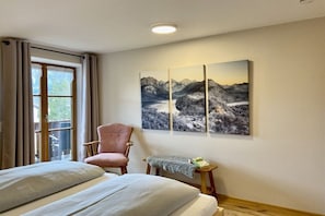 Ein Hotelzimmer mit Bett, einem Sessel, einem kleinen Tisch mit einem Buch und einem Fenster mit Vorhängen.