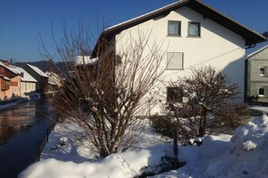 Ein Wohngebäude mit geneigtem Dach, einem sichtbaren Fenster und verschneitem Grund.