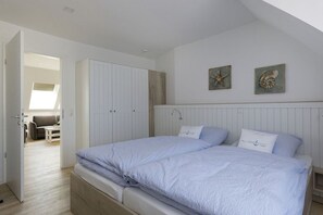 A bedroom with a large bed, a wardrobe, and a view of a living area. - Holiday apartment with 1 bedroom (Cuxhaven)