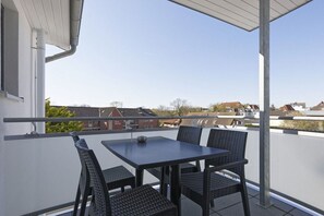 A balcony with a table and chairs, overlooking a residential area. - Holiday apartment with 1 bedroom (Cuxhaven)