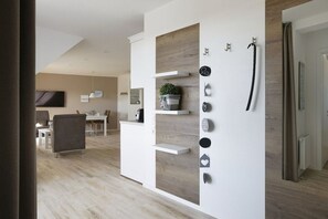 Una sala moderna con pared decorada en blanco y madera, un televisor de pantalla plana y un comedor con mesa y sillas.