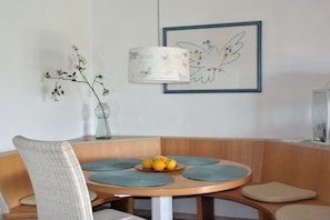 A dining area with a round table, a vase with branches, and a framed artwork on the wall. - Holiday home Lechseeferien II (Lechbruck am See)