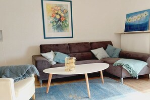 A living room with a brown sofa, a round coffee table, and a blue rug. - Holiday home Lechseeferien II (Lechbruck am See)