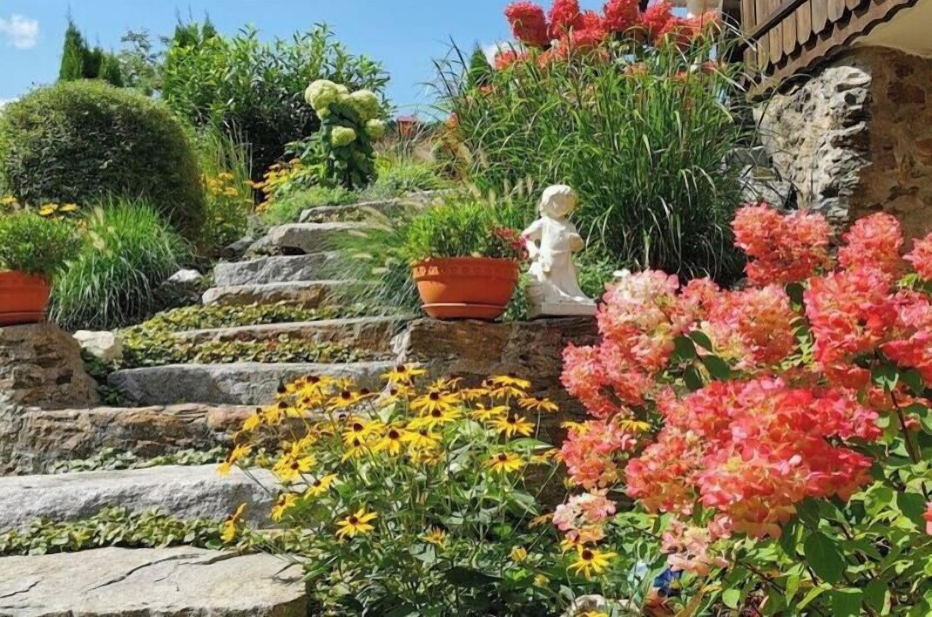 A garden with stone steps, potted plants, and a statue.