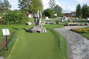 A statue in a landscaped area with a paved path and a sign. - Holiday home "Buchenberg" (Lechbruck)