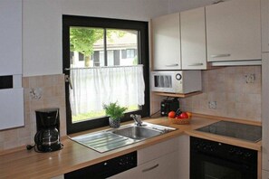 A kitchen with a window, a coffee maker, a sink, a microwave, and a stove. - Holiday home "Buchenberg" (Lechbruck)